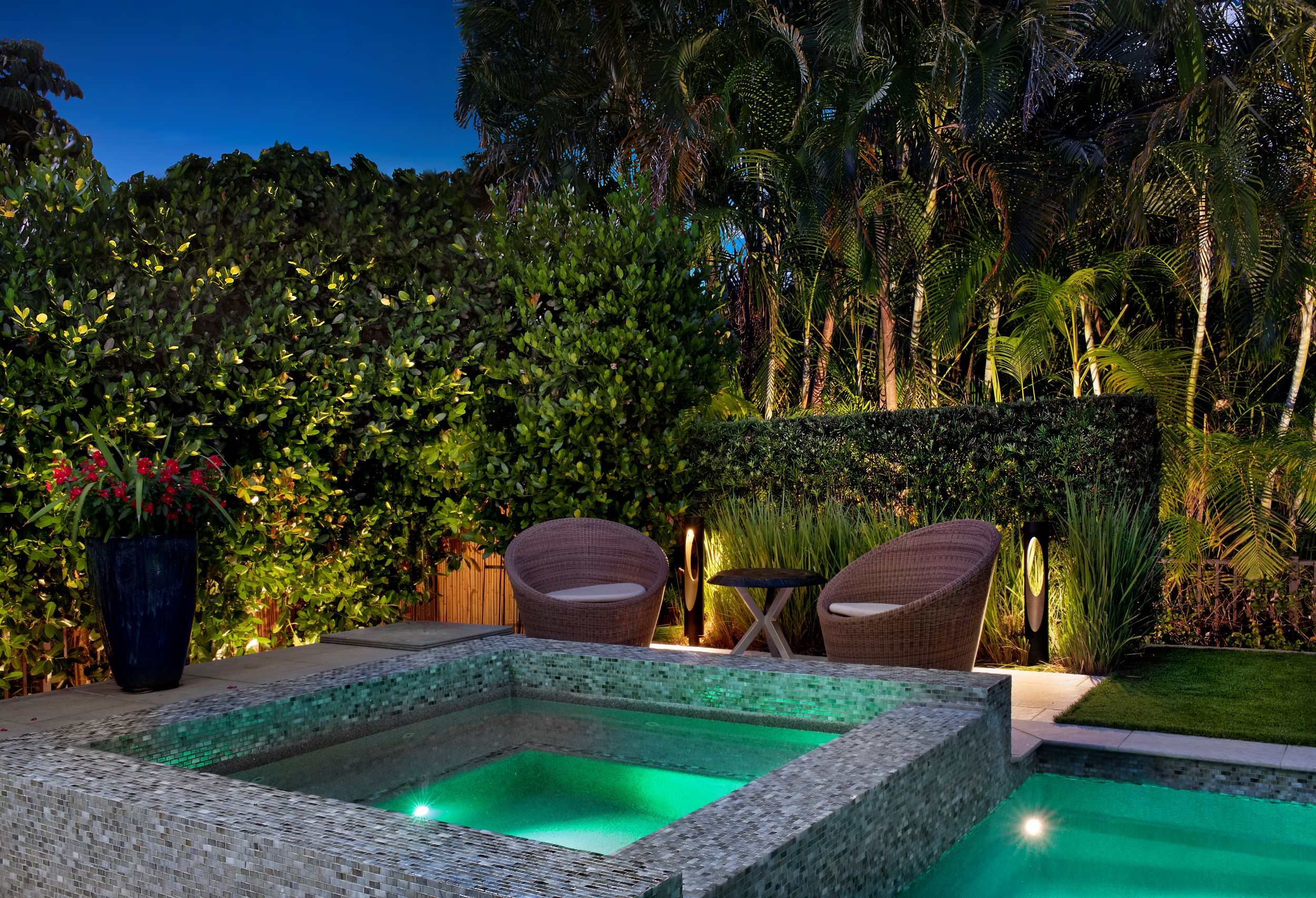 Landscape lighting illuminating pool deck with up-lighting and modern path-lights.